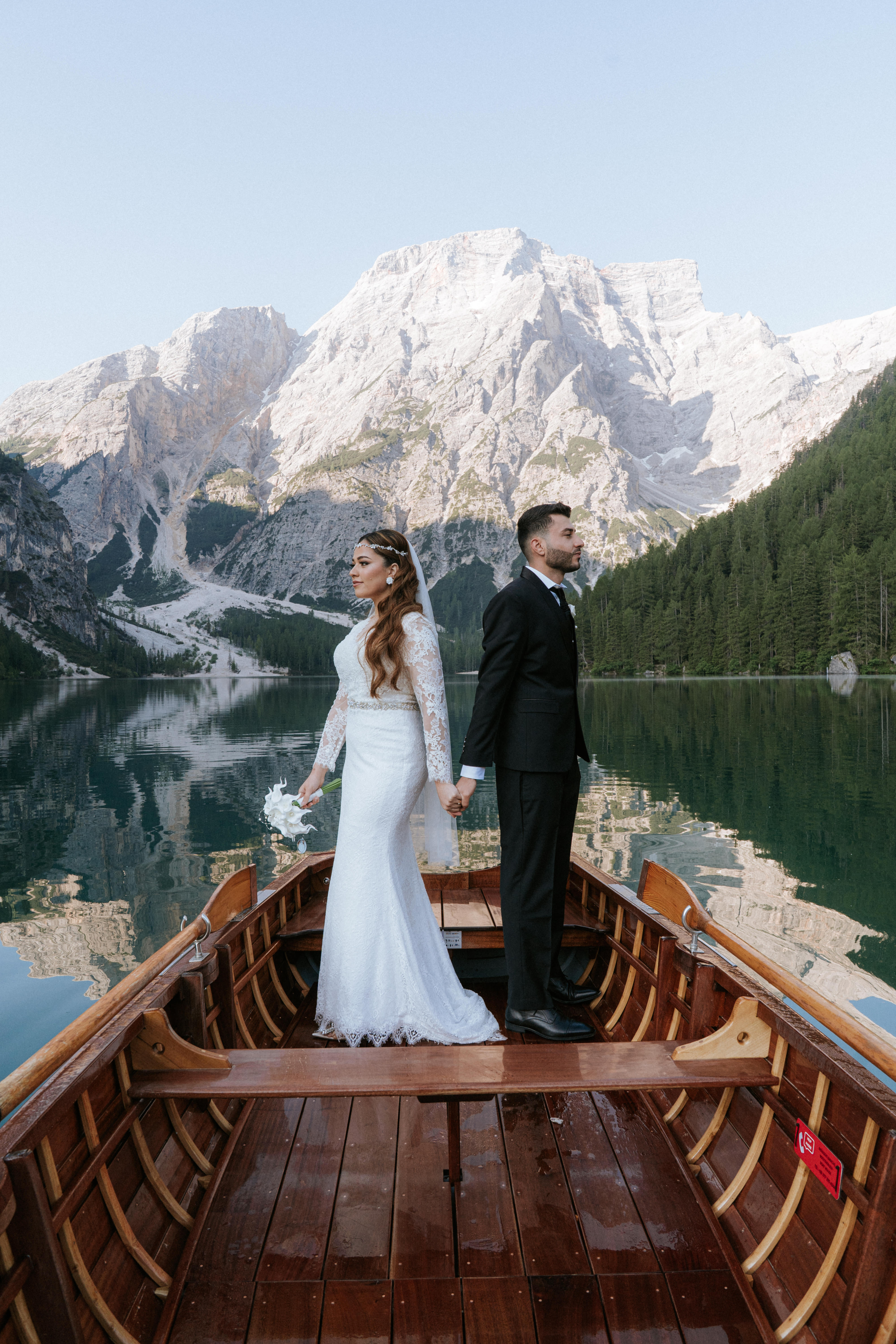 Bride with a flowing wedding dress at Lago di Braies with the lake and Dolomites reflected in the calm water – Lago di Braies wedding photographer