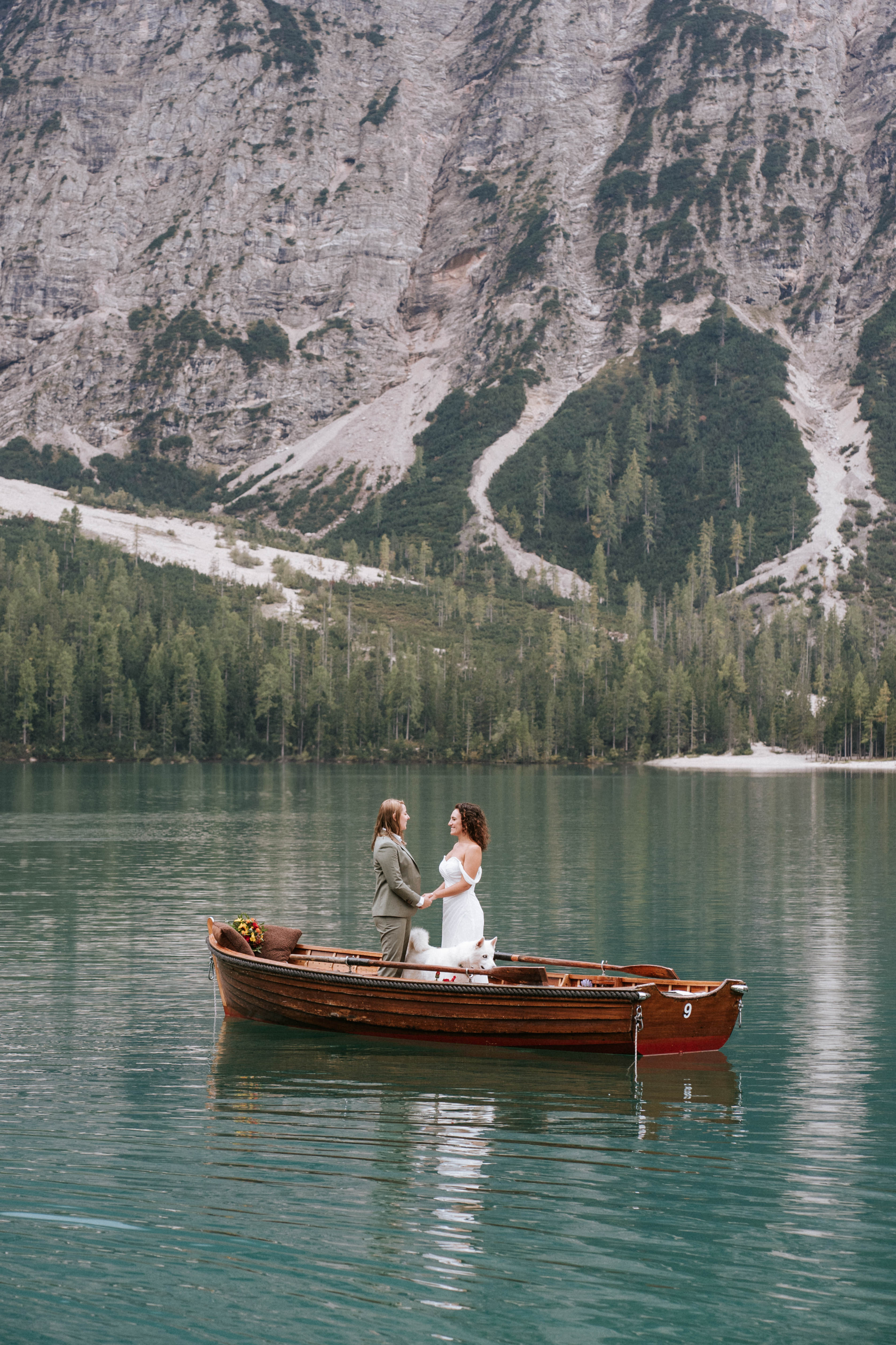 Couple walking along the shore of Lago di Braies with the Dolomite peaks towering above – Lago di Braies elopement photographer South Tyrol