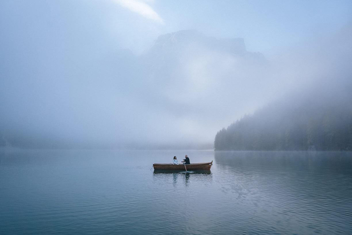 A couple in a wooden boat on the turquoise waters of Lago di Braies, surrounded by towering Dolomite peaks.